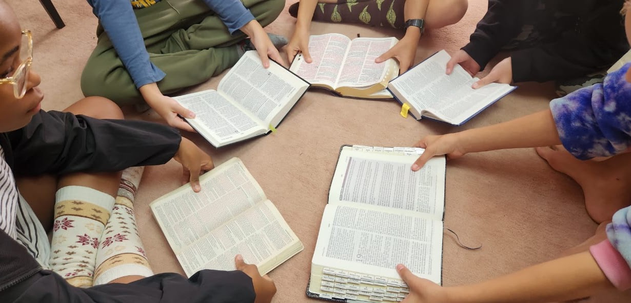 Learners gathered around open Bibles during Bible study.